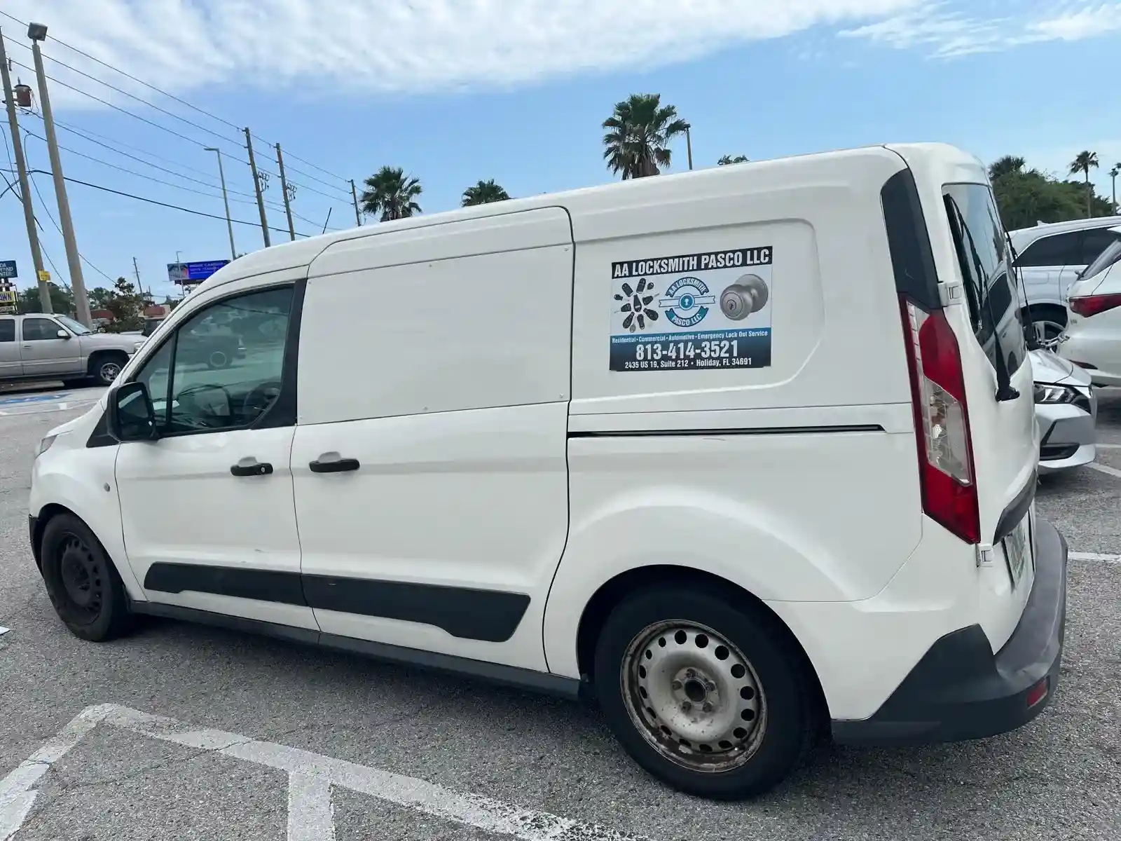 A white locksmith service van parked in a parking lot, ready for service.