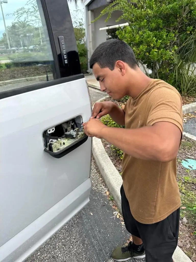 A man repairing the door handle of a white van, focusing on car lock repair.