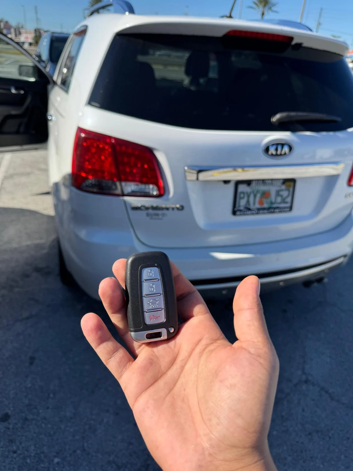 A person holding a keyless entry remote control for a car, ready to unlock or start the vehicle.