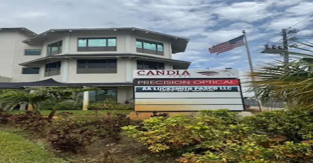 xterior view of the Candia Tower office building in Holiday, Florida, featuring signage for AA Locksmith Pasco LLC, with an American flag waving nearby and landscaped greenery in the foreground