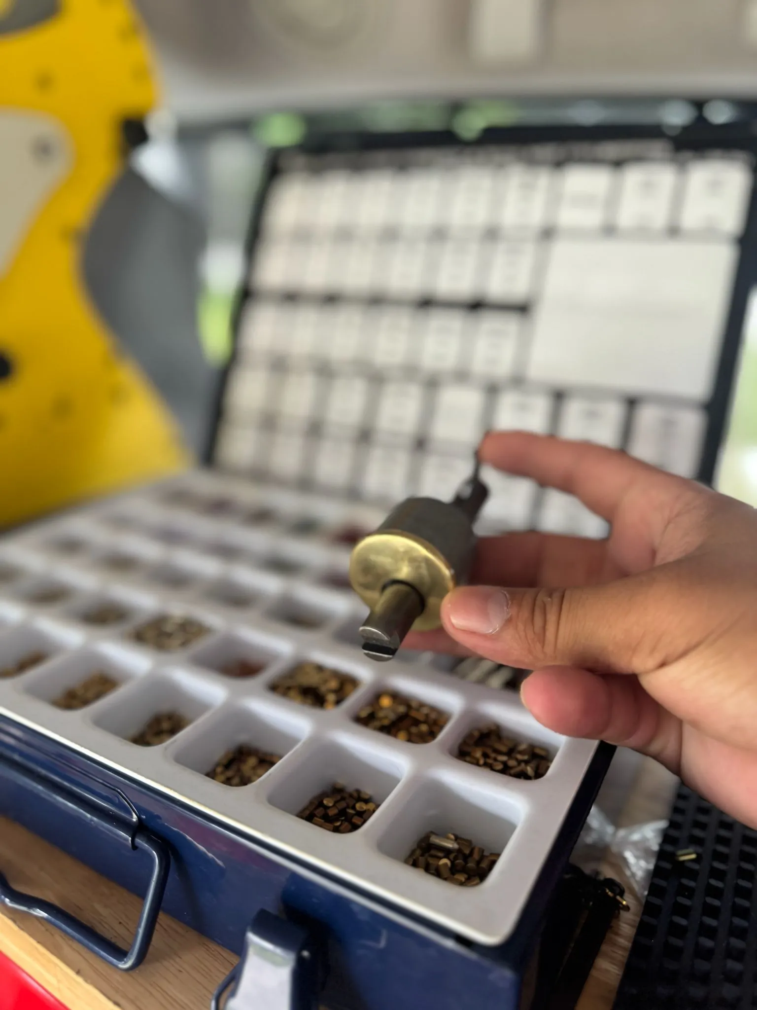 A locksmith from AA Locksmith Pasco LLC holding a lock cylinder pinning tool over a tray of lock pins, representing professional residential locksmith service.