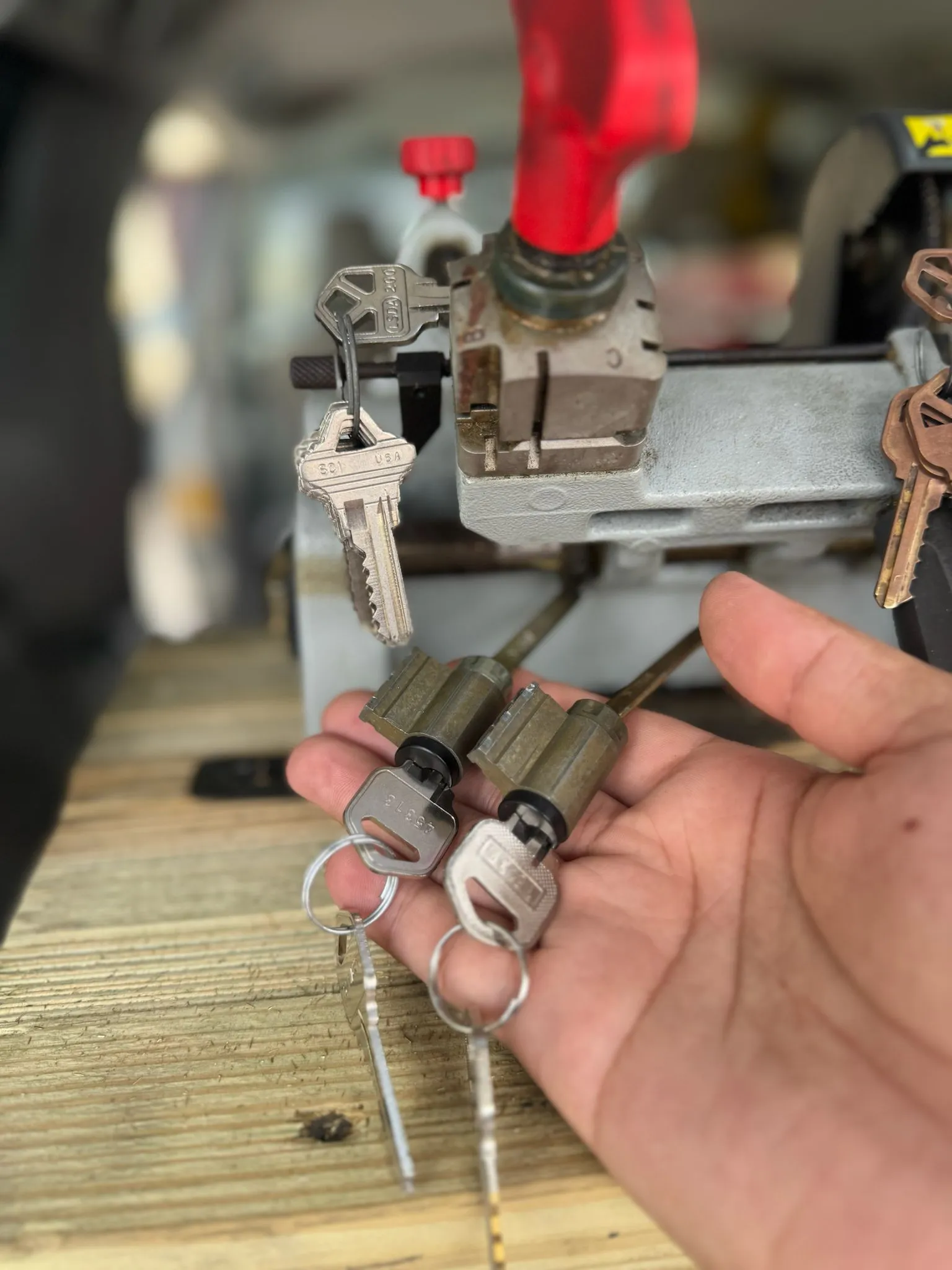 A locksmith from AA Locksmith Pasco LLC holding repaired lock cylinders and keys beside a key-cutting machine, representing professional commercial lock repair service.